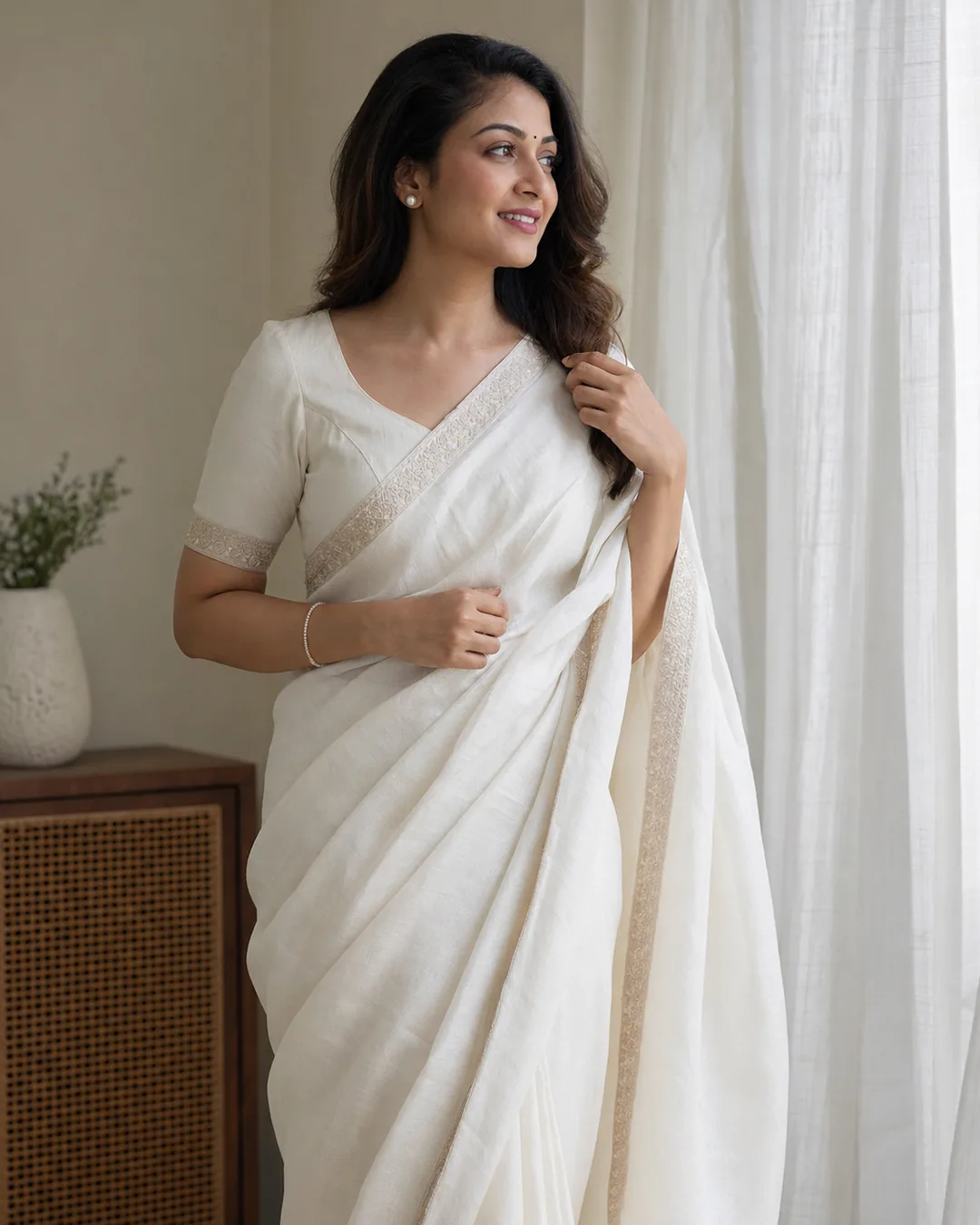 Adult Indian woman in a white saree near a softly lit window